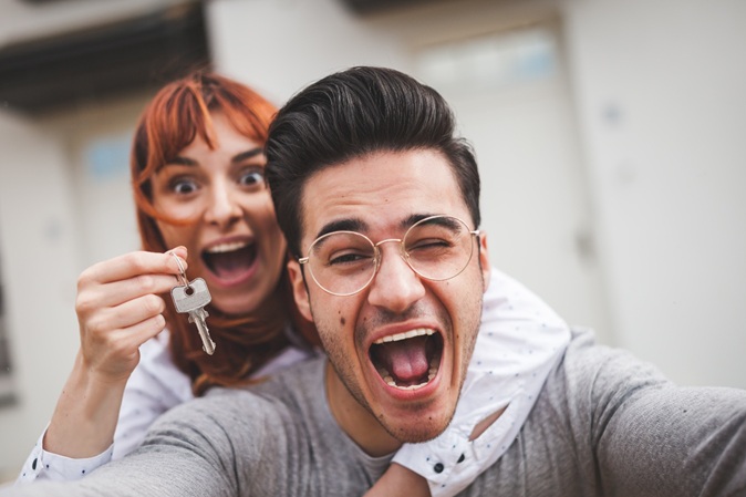 Excited,Couple,With,Keys,To,Their,New,Home,Hugging,And